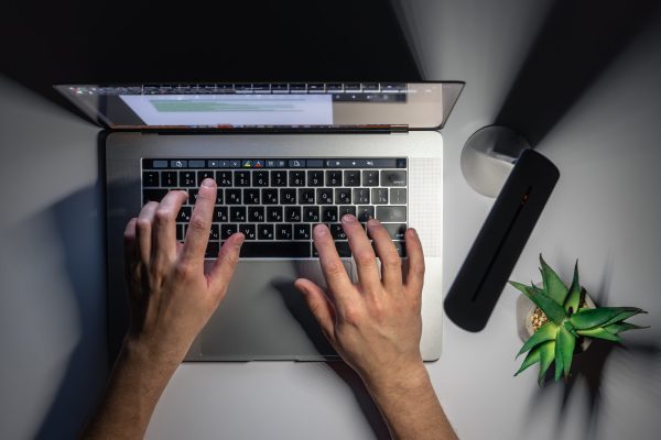 A man uses a laptop at night, hands close-up, night work, computer addiction, top view.